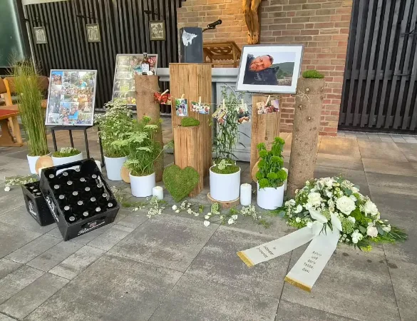 Trauerfeier mit Porträt, Blumen, Fotos und einem Herz aus Moos
